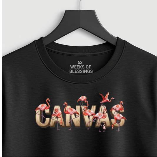 Black t-shirt with flamingo design and text on a hanger against a white background